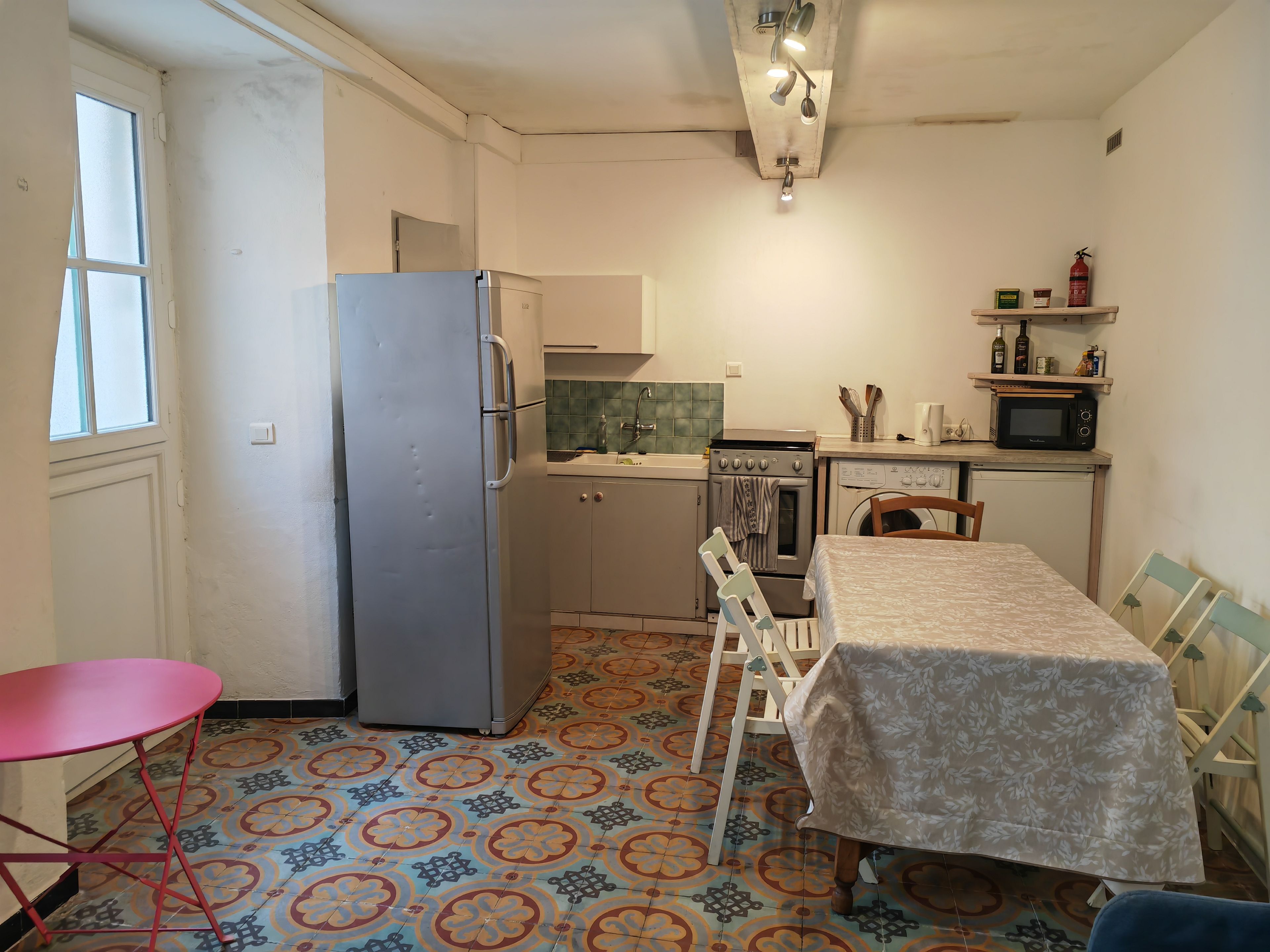 A compact kitchen with a refrigerator, oven, microwave, and a dining area with a table and chairs.