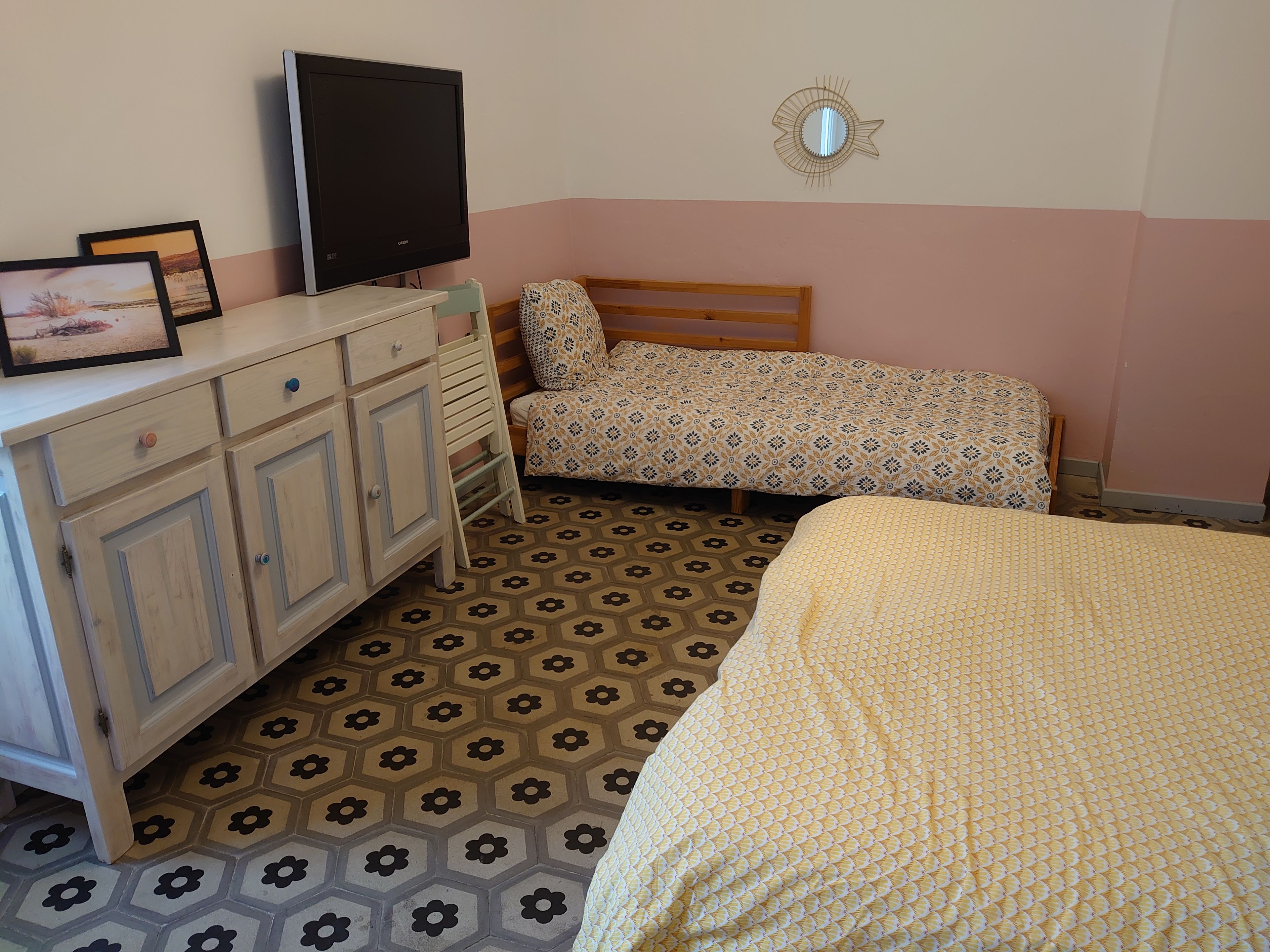 Ein Schlafzimmer mit einem Bett, einem Schreibtisch, einem Fernseher und einem gemusterten Boden.
