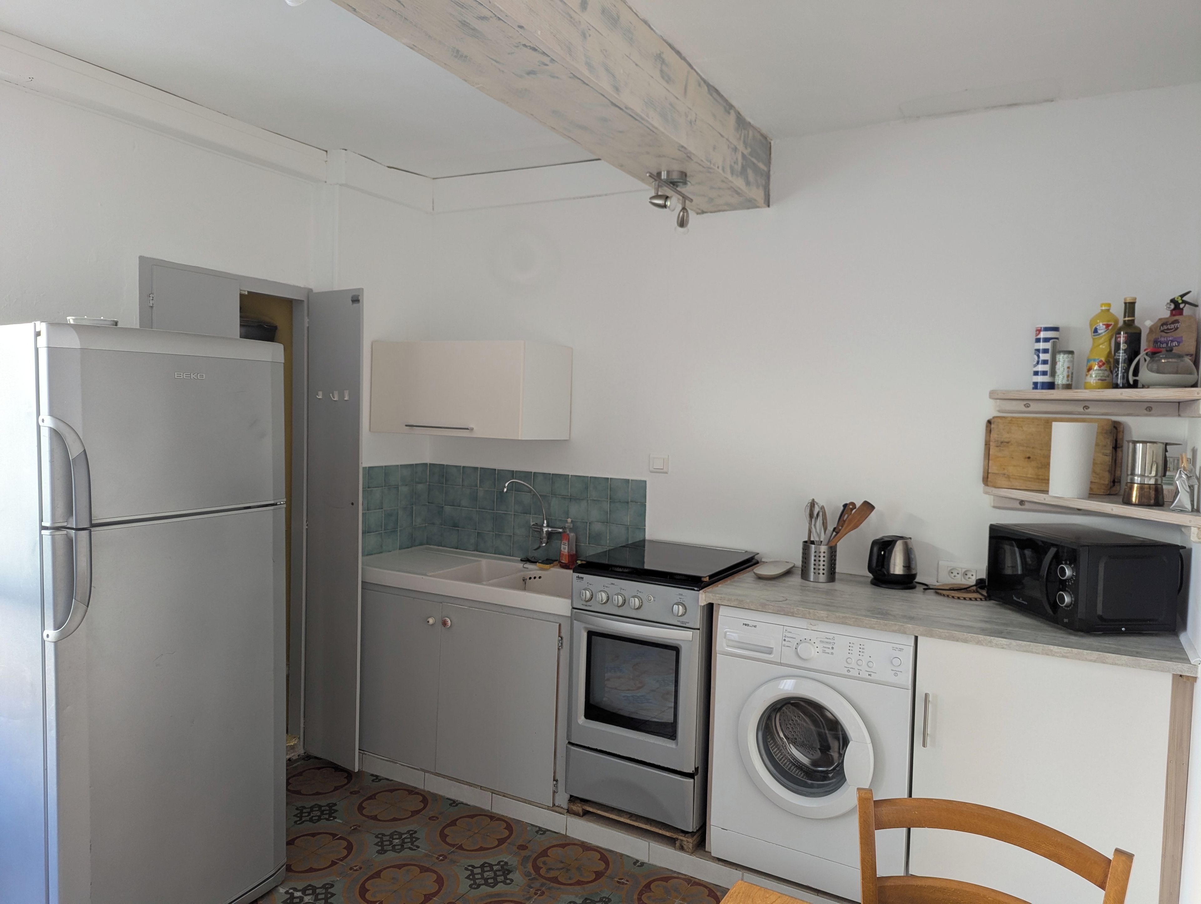 Una cucina compatta con frigorifero, forno, microonde e lavatrice.