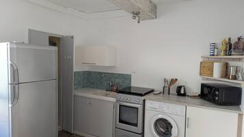 Una cucina compatta con frigorifero, forno, microonde e lavatrice.