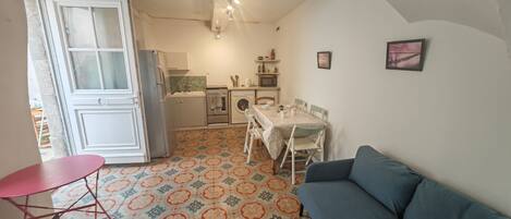 A compact living space with a kitchenette, a dining area, and a sofa.