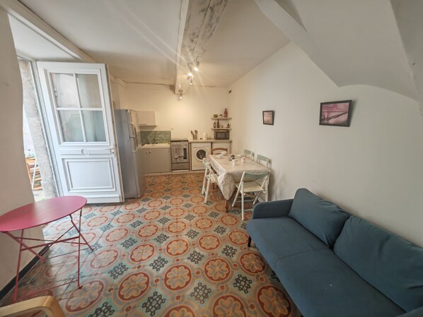 A compact living space with a kitchenette, a dining area, and a sofa.