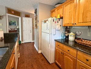 A kitchen with wooden cabinets, a white refrigerator, and a countertop with various items. - 2 bed condo, Seven Devils, close to it all! (Seven Devils)
