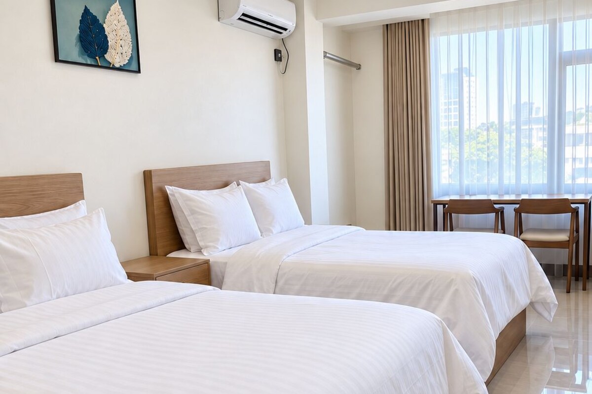 A hotel room with two beds, a desk, and a chair.