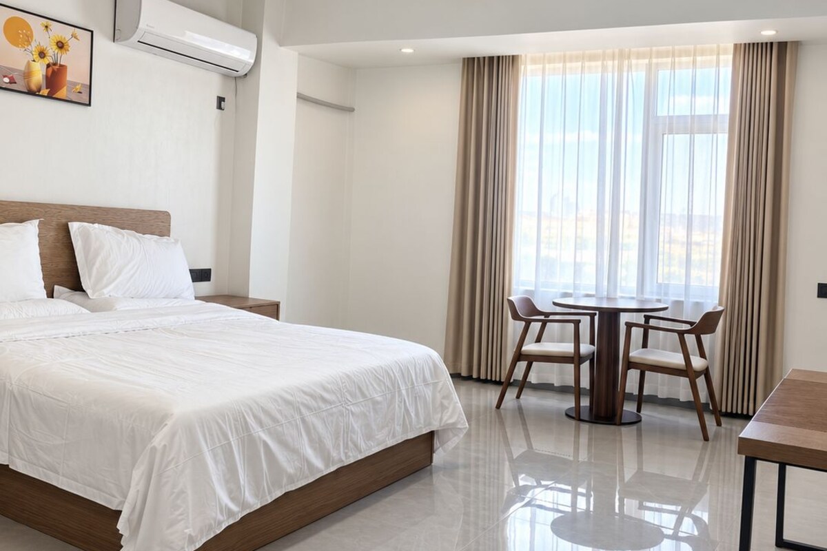 A hotel room with a bed, a dining table, and a chair.