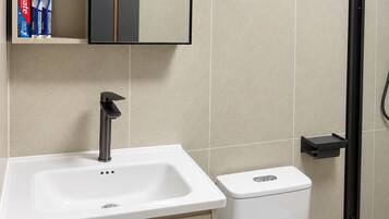 A modern bathroom with a white sink, a toilet, and a mirror above the sink.