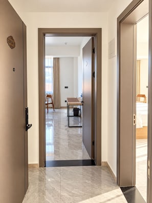 A hotel hallway with a marble floor, a wooden table, and a bed in the background. - No.1 Diamond Hotel (Golden Grove)