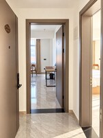 Un pasillo de hotel con piso de mármol, una mesa de madera y una cama al fondo.