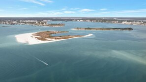 An aerial view of a coastal area with a large body of water, several small islands, and a distant cityscape. - Caribe BldgB-Fully Updated-Great Gulf Views-Orange Beach-Signature Properties (Orange Beach)