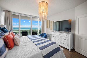 A hotel room with a large bed, a television, a dresser, and a balcony with a view of the ocean. - Caribe BldgB-Fully Updated-Great Gulf Views-Orange Beach-Signature Properties (Orange Beach)