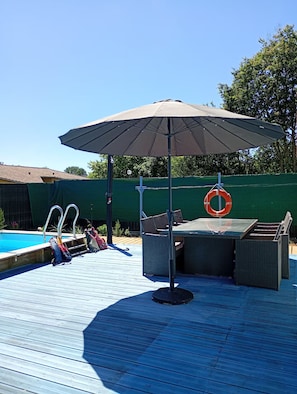 A poolside area with a table and chairs, a pool, and a lifebuoy. - House with a pool in a quiet location (Saint-Michel-Escalus)