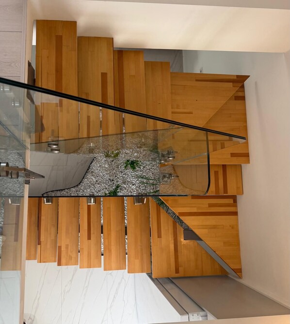 A modern staircase with wooden panels and glass railings. - LUNA MARE REZİDANS (FİNİKE)