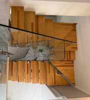 Una escalera moderna con paneles de madera y barandas de vidrio.
