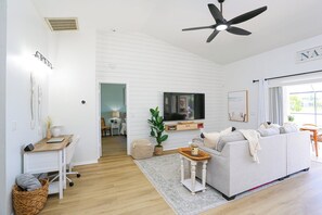 Una sala de estar moderna con televisor de pantalla plana, ventilador de techo y sofá.
