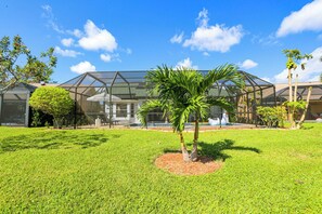 Una propiedad residencial con una estructura de vidrio, césped cuidado y una palmera.