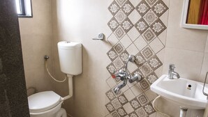 A bathroom with a toilet, a wall-mounted sink, and a shower. - Shri Radha Govind Bhakt Niwas and Hotel (Pandharpur)