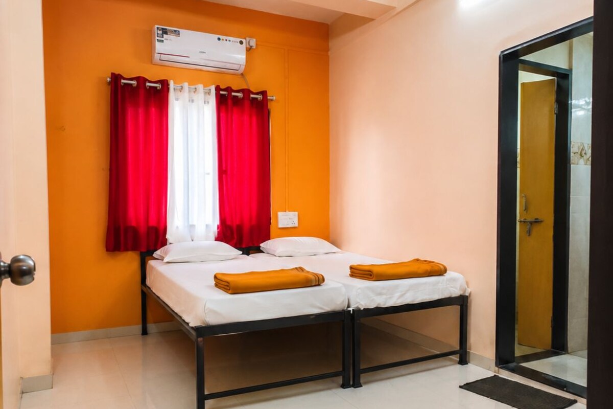 A small, single-bed room with a ceiling fan, an air conditioning unit, and a sliding glass door leading to a bathroom.