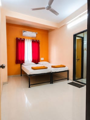 A small, single-bed room with a ceiling fan, an air conditioning unit, and a sliding glass door leading to a bathroom.