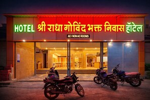 Hotel com placa indicando quartos com e sem ar condicionado, e duas motocicletas estacionadas em frente.