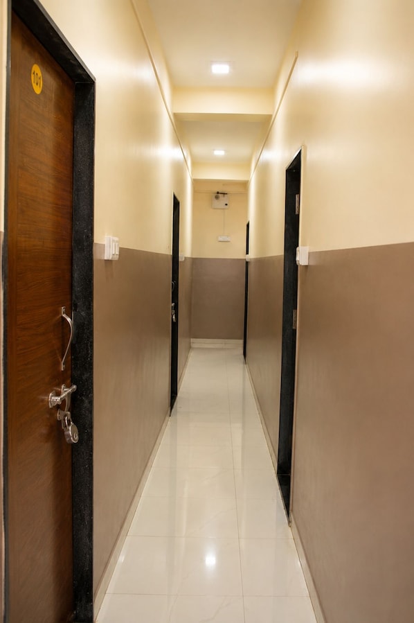 A corridor with doors on both sides, a tiled floor, and a light-colored wall.