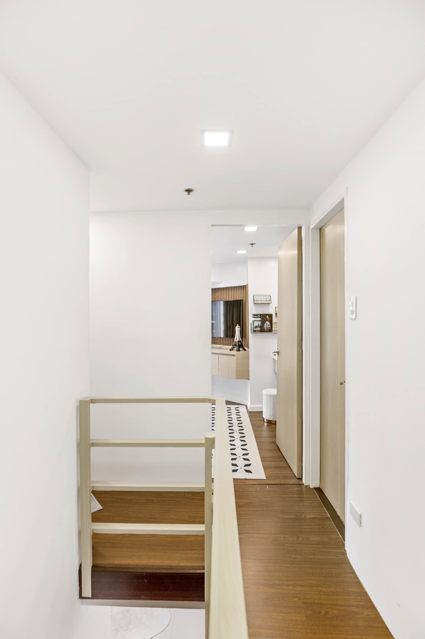 A modern interior with a wooden floor, white walls, and a staircase.
