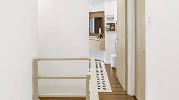 A modern interior with a wooden floor, white walls, and a staircase.