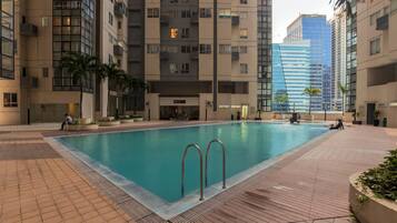 A swimming pool surrounded by high-rise buildings, with a few people around.