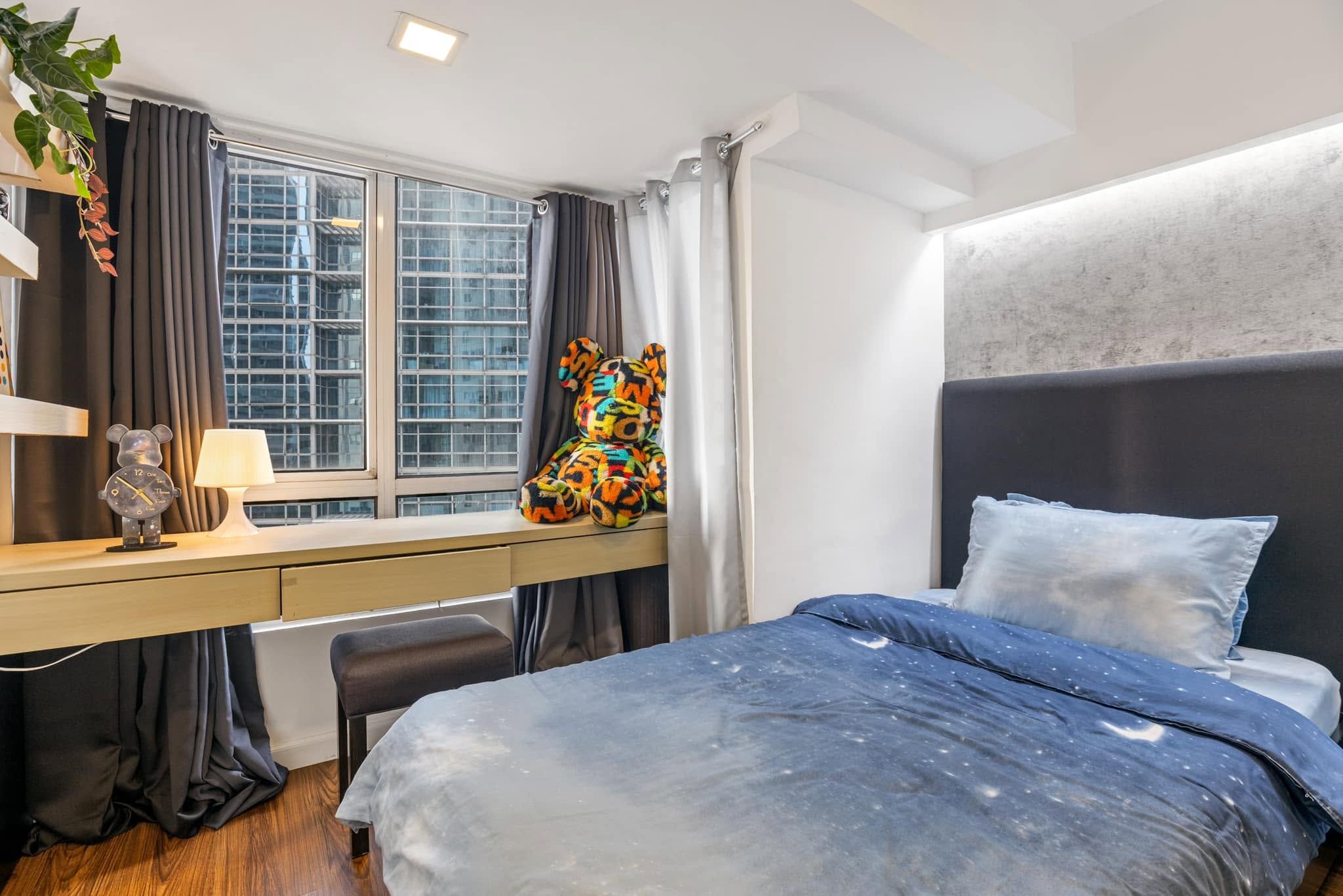 A modern bedroom with a bed, desk, and a window with curtains.