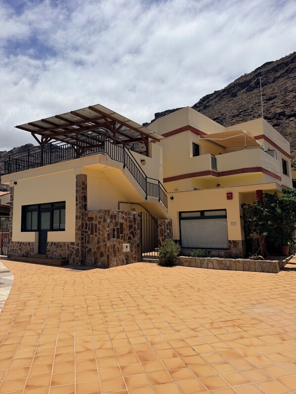 Una casa de dos pisos con fachada de piedra, un balcón cubierto y un garaje.