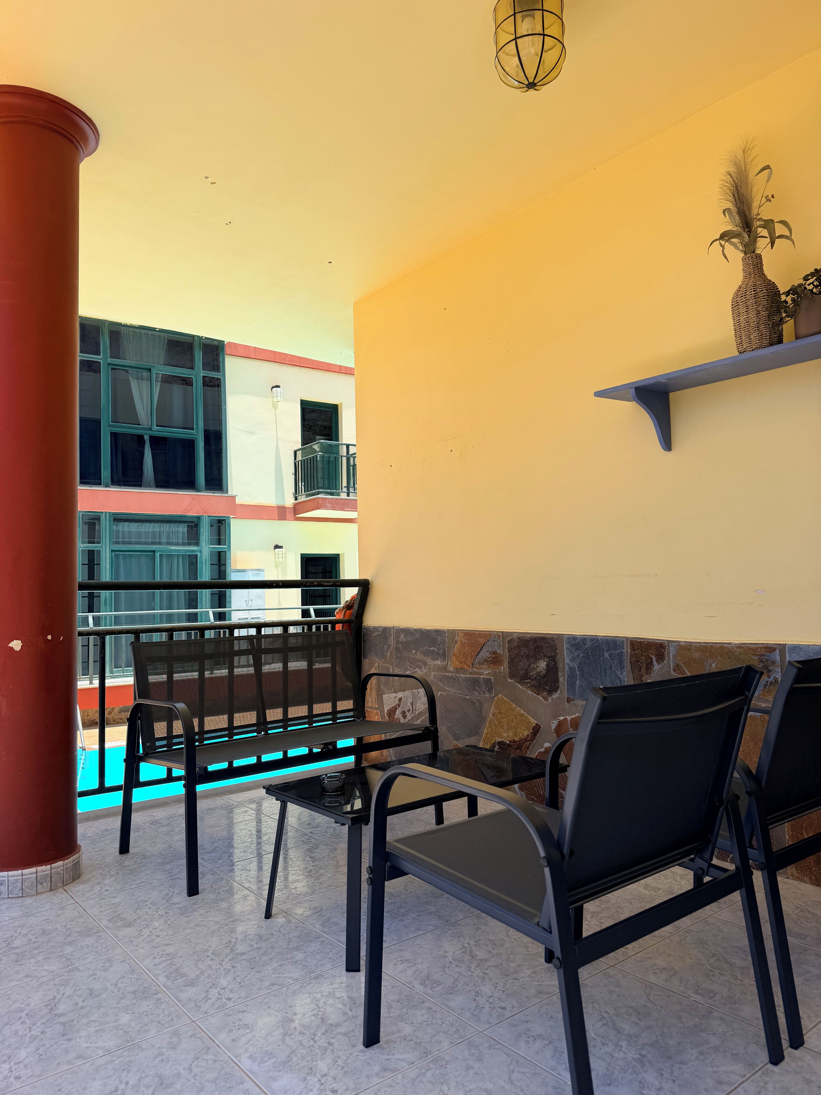 Eine Terrasse mit Pool, Sitzgelegenheiten im Freien und Blick auf ein Gebäude mit Balkonen.