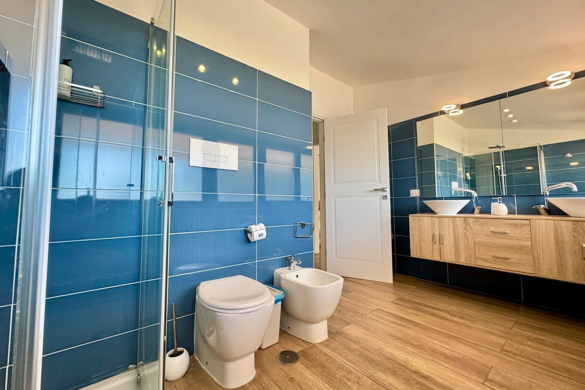 Un baño moderno con cabina de ducha de vidrio, inodoro, bidé y tocador con espejo.