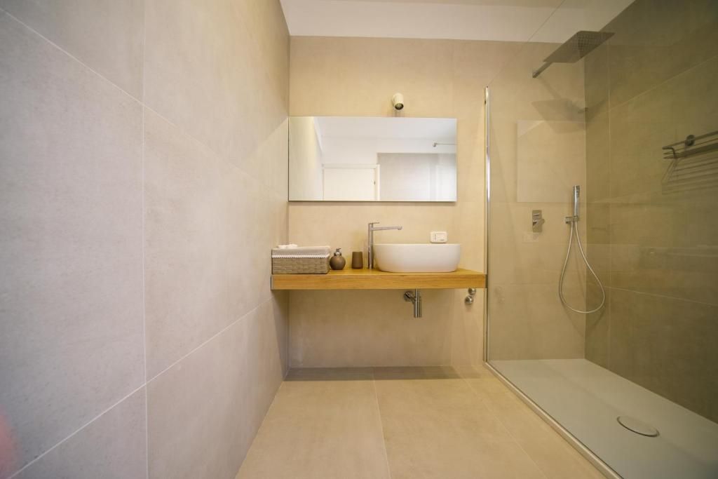 Een moderne badkamer met een douchecabine van glas, een wit wastafelmeubel en een spiegel erboven.