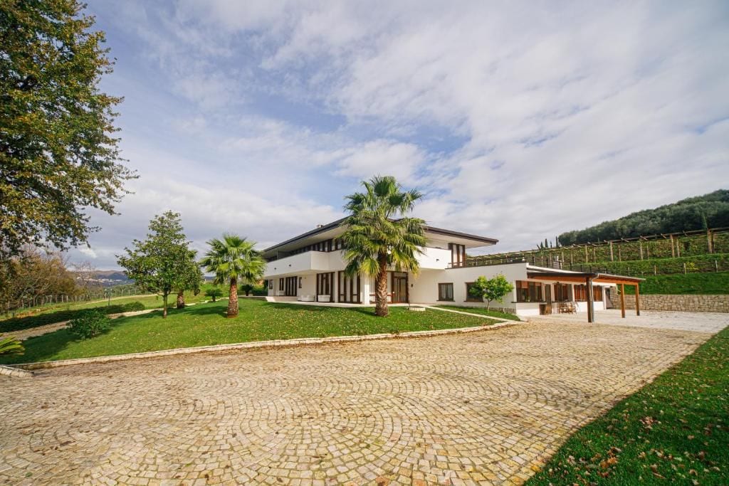 Una casa moderna de dos pisos con entrada pavimentada y césped cuidado.