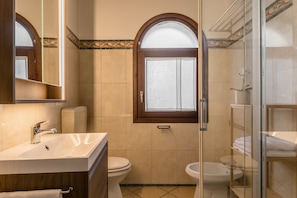 Ein Badezimmer mit Waschbecken, Toilette und Bidet, ausgestattet mit einem Holzmöbel und einer Duschkabine aus Glas.