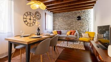 Un salon moderne avec un mur en pierre, un plafond en bois et un coin repas comprenant une table et des chaises en bois.