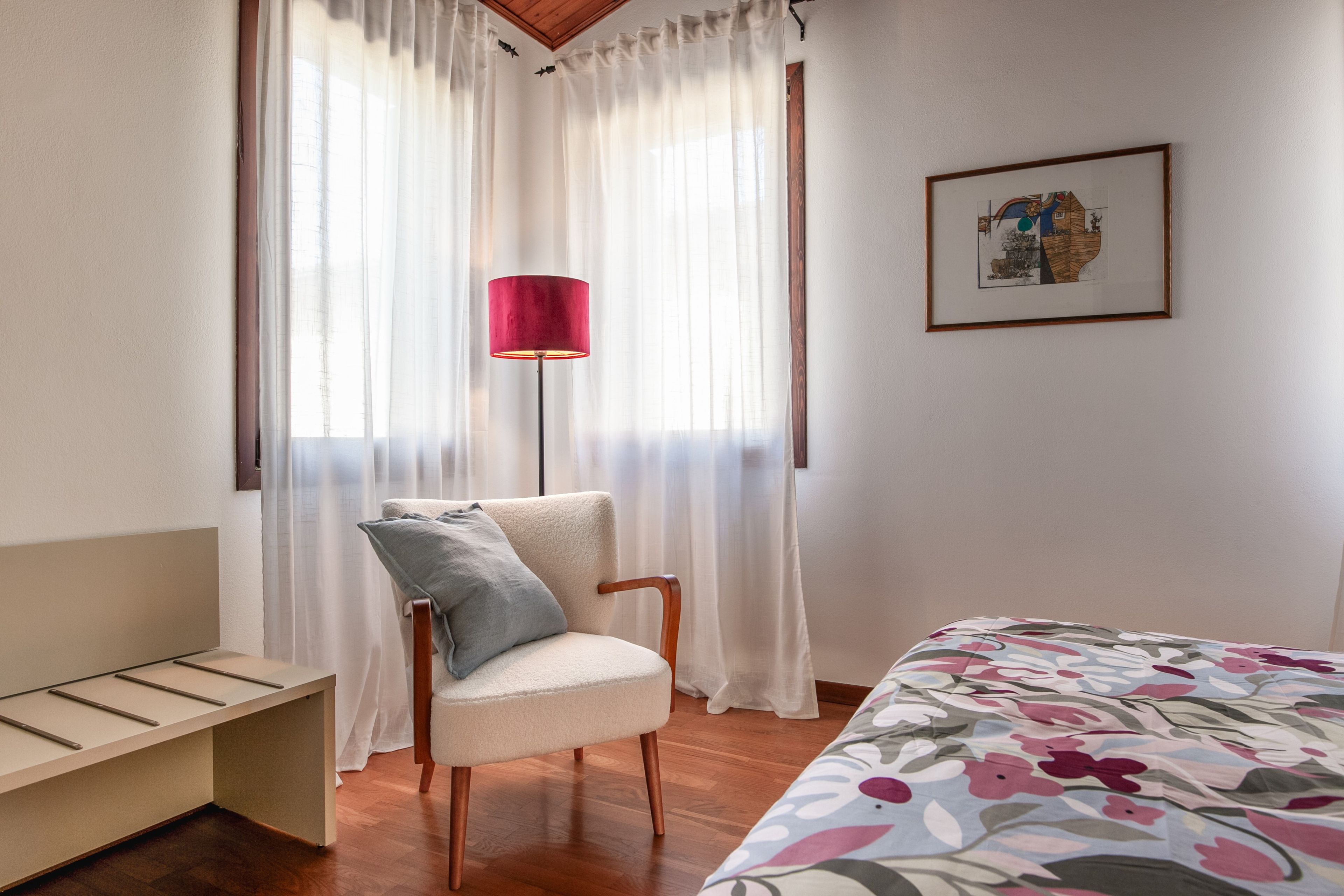 Ein Schlafzimmer mit Bett, Stuhl, Schreibtisch und Lampe.