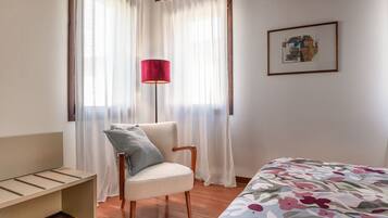 Ein Schlafzimmer mit Bett, Stuhl, Schreibtisch und Lampe.
