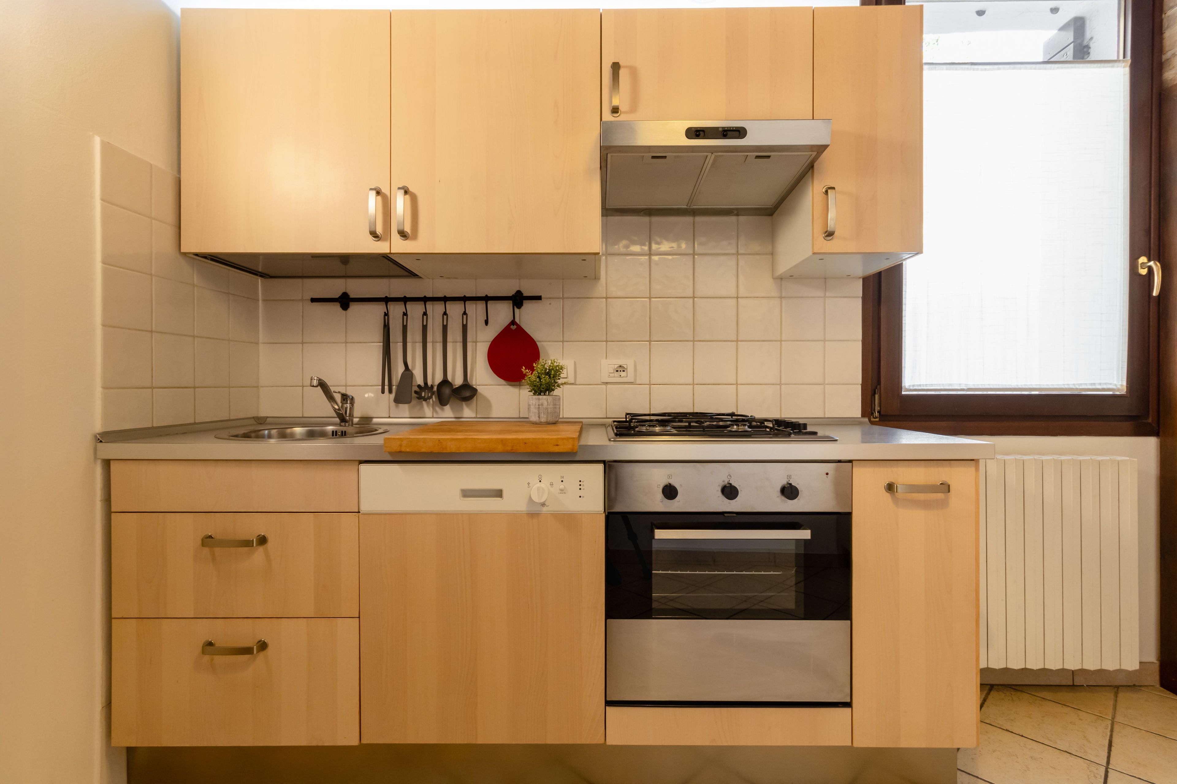 Une cuisine avec des meubles de rangement en bois, un évier en acier inoxydable, une cuisinière et un four.