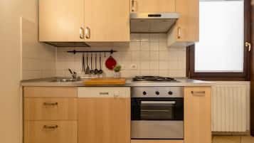 Une cuisine avec des meubles de rangement en bois, un évier en acier inoxydable, une cuisinière et un four.