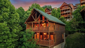A multi-story log cabin with balconies, surrounded by dense forest. - Cubby Bear Cabin • Cabin with Mountain Views • Pool Table & Arcade (Sevierville)