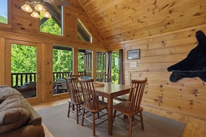 A wooden interior with a dining table and chairs, large windows, and a mounted animal head. - Cubby Bear Cabin • Cabin with Mountain Views • Pool Table & Arcade (Sevierville)