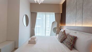 Ein modernes Hotelzimmer mit einem großen Bett, einem Nachttisch, einem Spiegel und Blick auf die Stadt durch das Fenster.