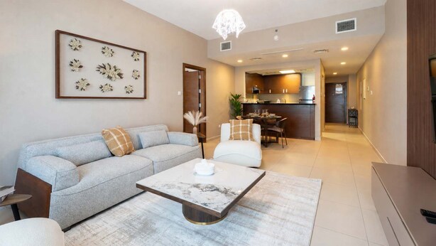 A modern living room with a sofa, coffee table, and a dining area with chairs. - Vanilla Homes Premium 1BR in Gate Tower (Abu Dhabi)
