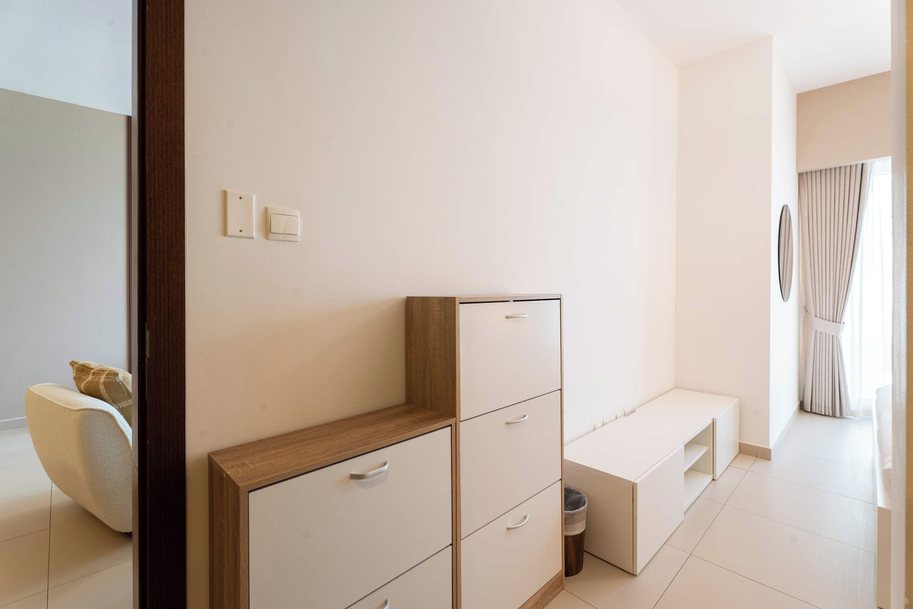 A modern, minimalist room with a built-in wardrobe, a bench, and a small trash bin.