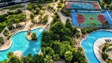 Ein Pool, umgeben von Palmen, und ein Basketballplatz.