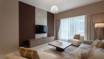 A modern living room with a flat-screen TV, a sofa set, a coffee table, and a decorative lamp.