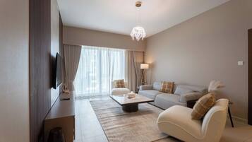 Un salon moderne comprenant un canapé, un fauteuil, une table basse et un téléviseur.