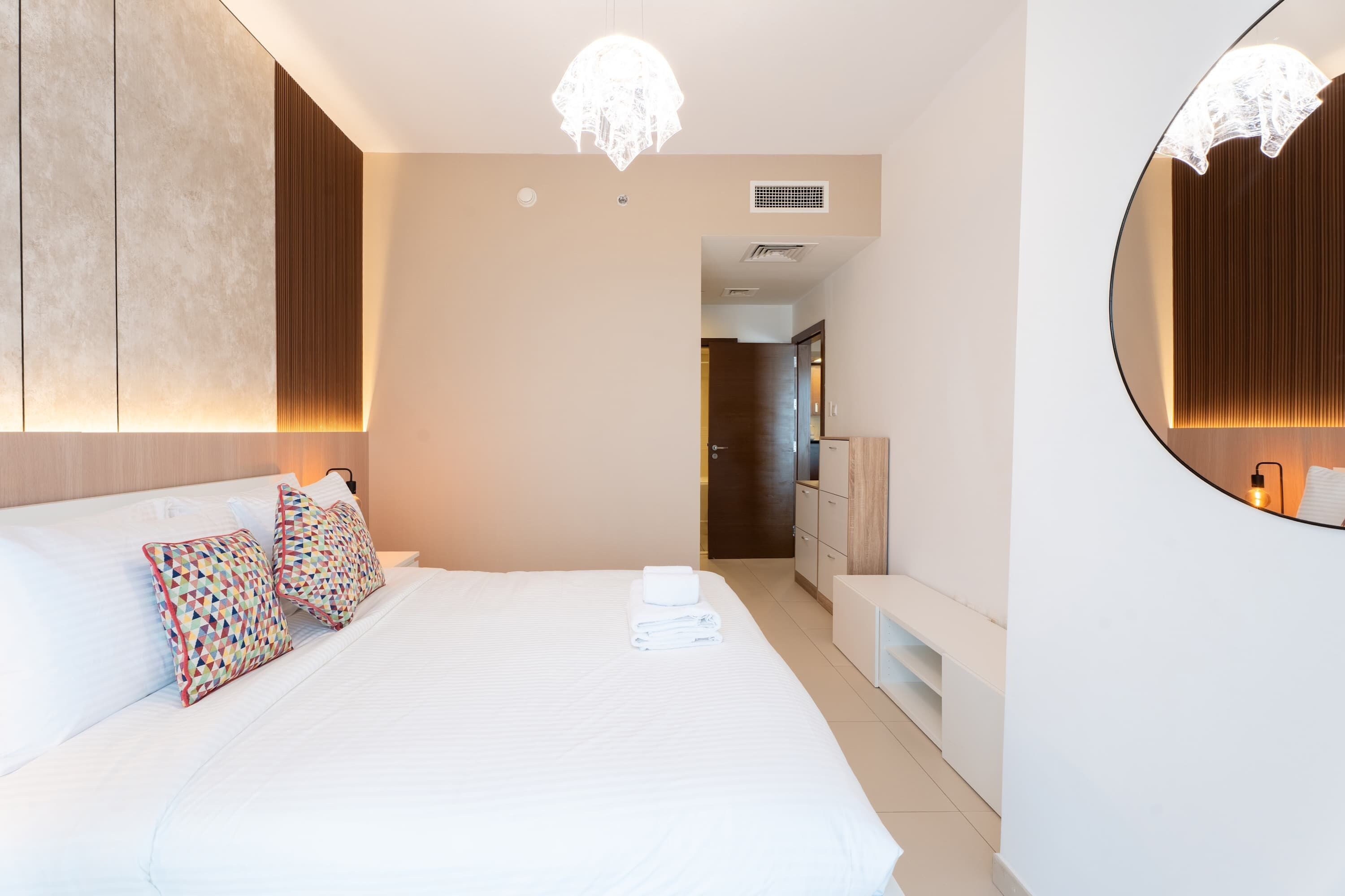 Une chambre d’hôtel moderne avec un grand lit, une table de chevet, un miroir et une vue sur la salle de bain.