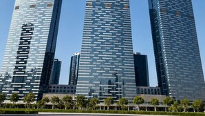 A modern skyscraper with a curved top and reflective glass facade. - Vanilla Homes Premium 1BR in Gate Tower (Abu Dhabi)