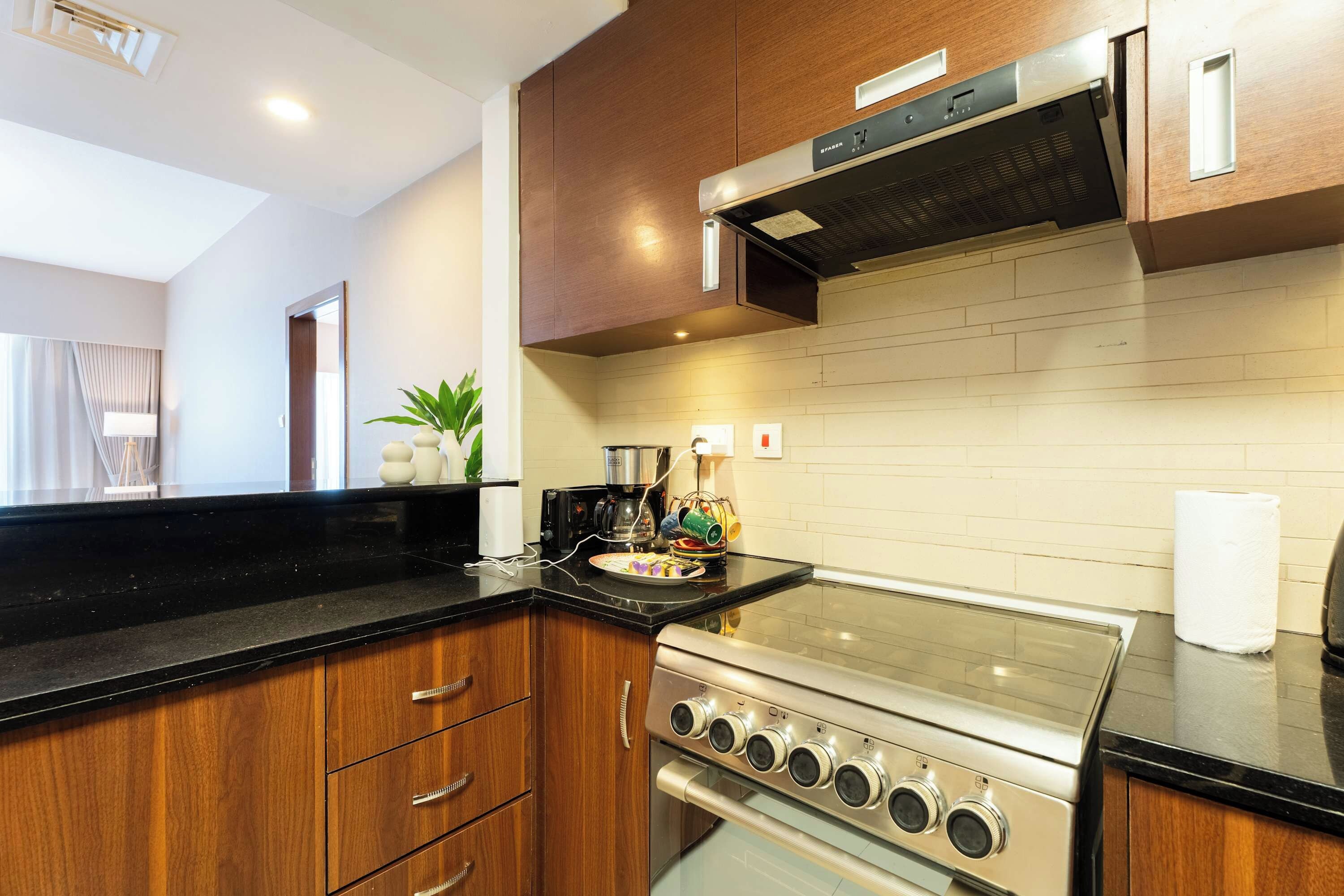 A modern kitchen with wooden cabinets, a stainless steel stove, and a black countertop.